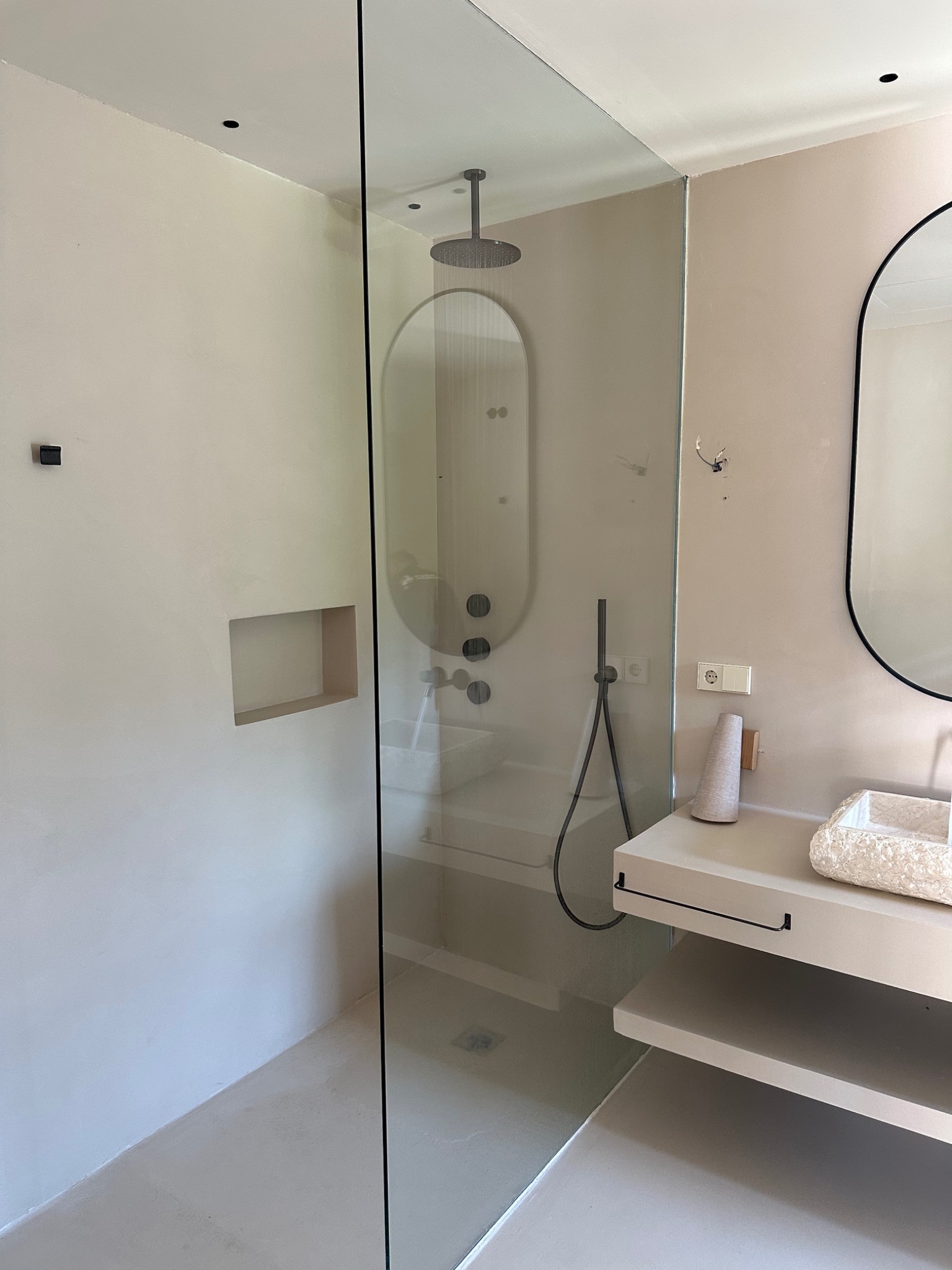 Ducha empotrada con mampara de vidrio en baño de villa